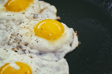 Vintage photo of Fried eggs in a frying pan. Process of cooking eggs closeup. Food Background