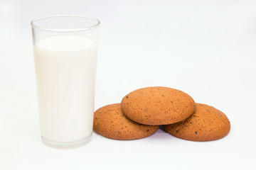 Milk and oat cookies. 
Closeup of a glass of milk and delicious oat cookies on white background.