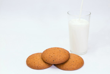 Oat cookies and milk. 
Closeup of delicious oat cookies and a glass of milk on white background.