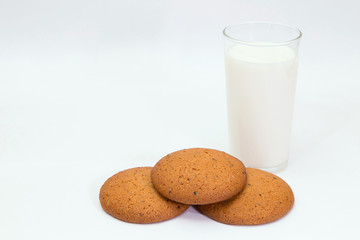 Milk and oat cookies. 
Closeup of delicious oat cookies and a glass of milk on white background.