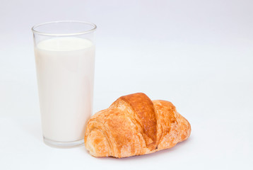 Milk and croissant. 
Closeup of a glass of milk and delicious croissant on white background.