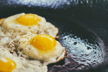 Vintage photo of Fried eggs in a frying pan. Process of cooking eggs closeup. Food Background