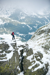 Naklejka premium Hiker standing on a rock. Winter landscape. Shot of a young hiker taking photos from the top of a mountain
