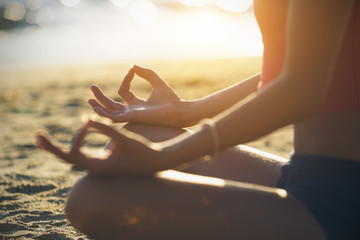 Young woman practicing yoga on the beach.