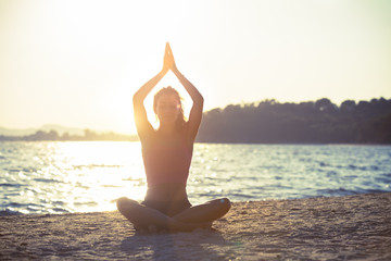 Fototapeta na wymiar Young woman practicing yoga on the beach.