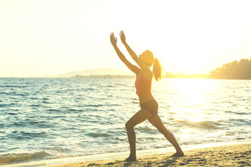 Fototapeta na wymiar Young woman practicing yoga on the beach.