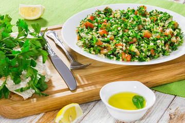 Tabbouleh parsley salad on white platter on chopping board