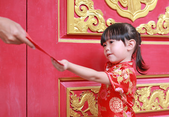 Woman hand giving red packet monetary gift for Cute little girl at chinese temple in bangkok,...
