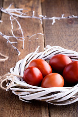 Easter red eggs in  willow tree wreath on rustic table
