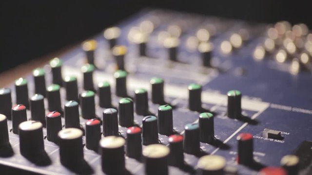 Close up video of a mixer desk with many buttons and shifting focus.