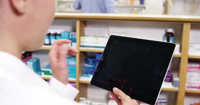 Pharmacist using digital tablet in pharmacy