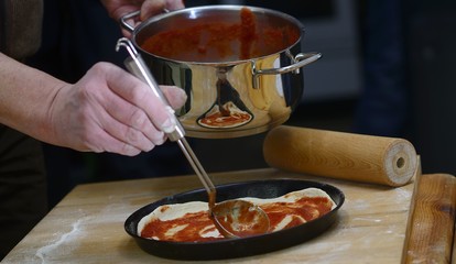 Hände arbeiten an einer Pizza