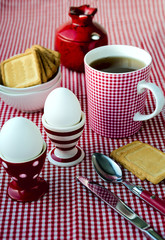 Hard boiled eggs, tea and cookies served in the dotted, striped and checkered red and white crockery