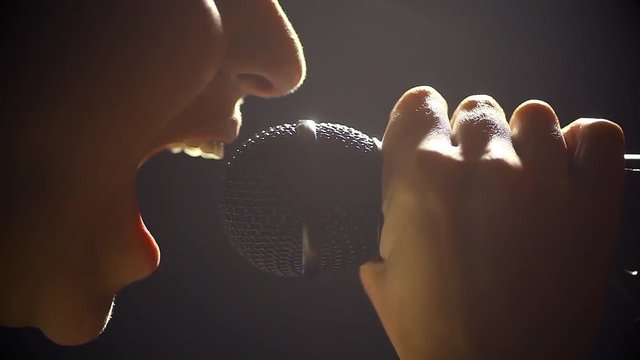 Close up image of a woman screaming to a microphone.