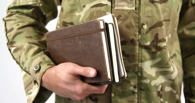 Mid section of soldier in military uniform holding dairy on white background 4k