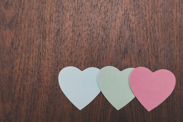 colored stickers in the shape of a heart on a wooden background