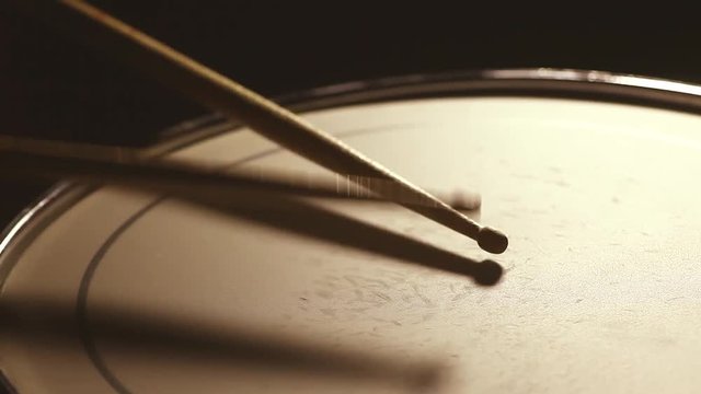 Close up footage of two drum sticks hitting a snare drum.
