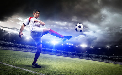 Fototapeta na wymiar Football player is kicking a ball in the stadium.