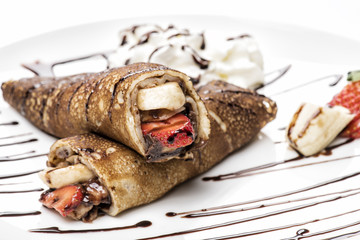 two folded crepes with strawberries, cream and chocolate sauce, isolated on white