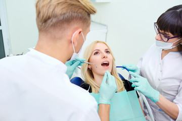 The patient is a girl with an open mouth at  dentist in  dental office.