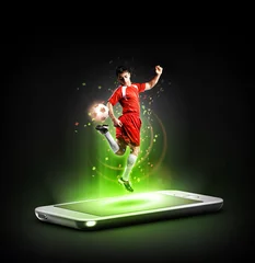 Gordijnen The football player in action on the phone, mobile football concept. © efks