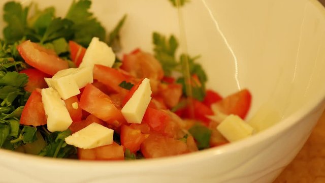 Vegetable lettuce salad. Olive oil pouring into bowl of salad. Italian Mediterranean or Greek cuisine.