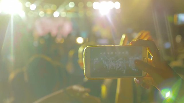 woman's hand filming with the smartphone a rock concert