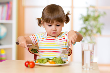 Cute little girl dining in kindergarten