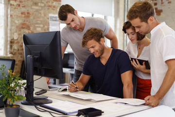 junges team im büro schaut gemeinsam auf unterlagen