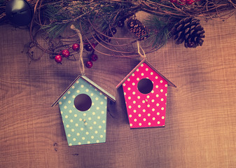 two birdhouses hang on pine with antique rustic wood background.