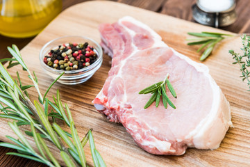 Raw meat on bone with rosemary, thyme, pepper and garlic