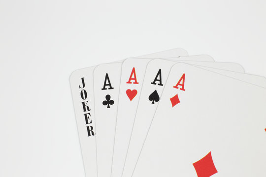 Playing cards - four aces and joker close up isolated in studio.