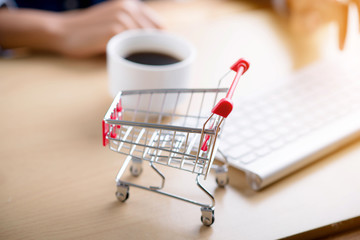 Shopping cart and coffee on wooden table,online shopping concept