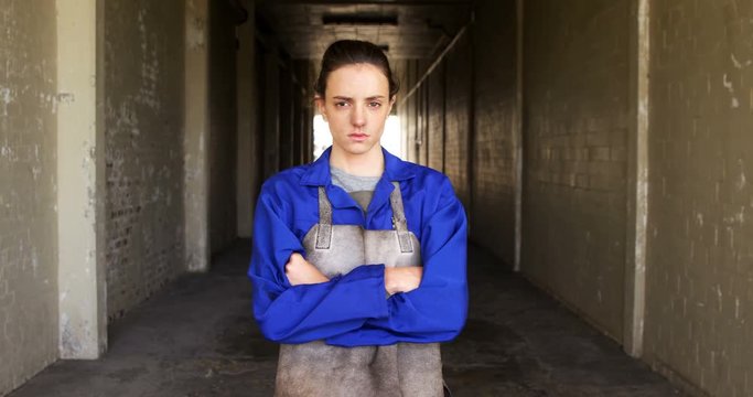 Portrait of female welder standing with arm crossed in workshop
