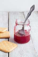 jam in a glass jar and crackers on a white background