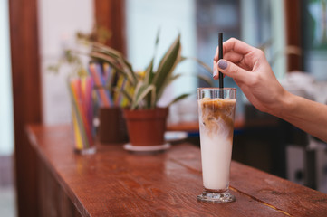 Ice coffee in a tall glass with cream poured