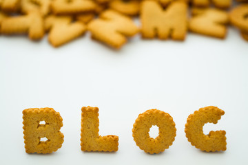 The word blog created from alphabet shaped cookies or biscuits on an isolated white background for a food blogger.
