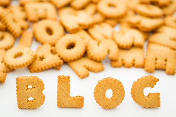 The word blog created from alphabet shaped cookies or biscuits on an isolated white background for a food blogger.