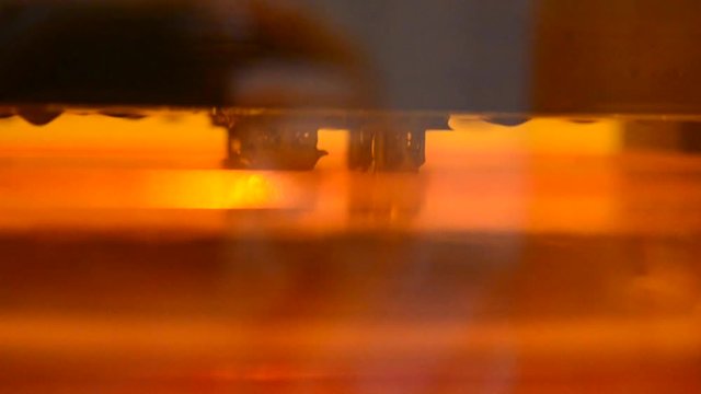 Stereolithography 3d printer printing detail of photopolymer close-up. Small elements overhanging sink in liquid material and harden under UV light. Modern additive technology of photopolymerization