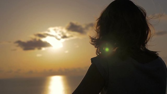 mysterious woman looks at the sea while the wind ruffles her hair
