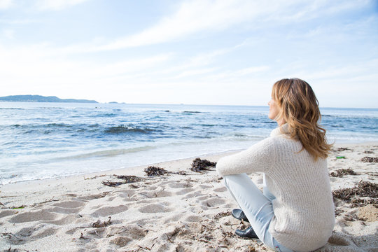 femme en hiver assise sur la plage