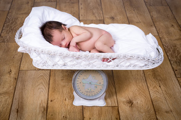 Beautiful naked baby girl on a baby scale