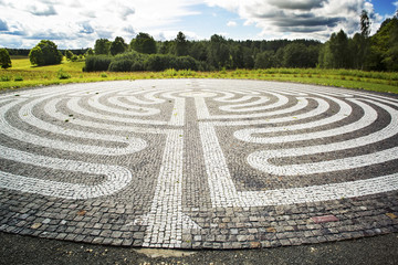 Fototapeta na wymiar Gothic labyrinth from black and white cobble-stones in the field. Europe. Letonia. Symbol of a new way, clarification