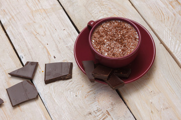 Milk chocolate in a cup on a saucer on a light wooden background