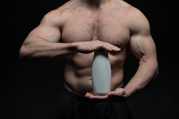 sexy muscular male torso of athlete man holds drink bottle
