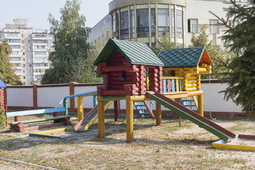 Colorful wooden house with slider on empty playground. Urban