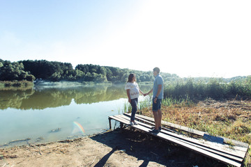 Magnetic young couple in casual clothes stands by the river