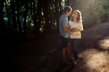 Adorable pregnant woman smiles to her man standing in the rays o