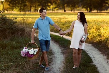 Fototapeta premium Happy man holds hand of tender pregnant woman while they walk al