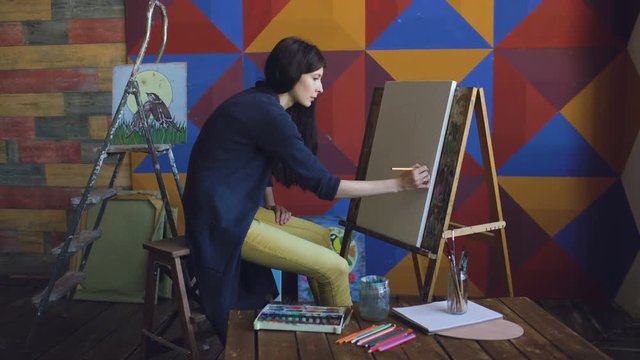 Young woman artist draw scetch wit pencil on easel canvas, preparing to paint picture